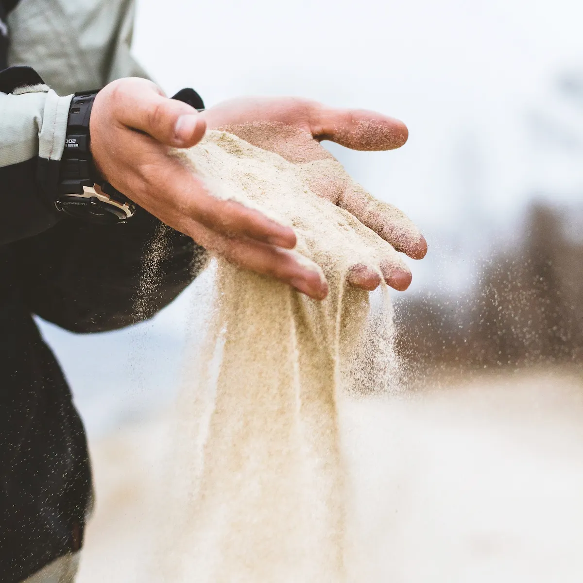 Hands with sand falling through the fingers